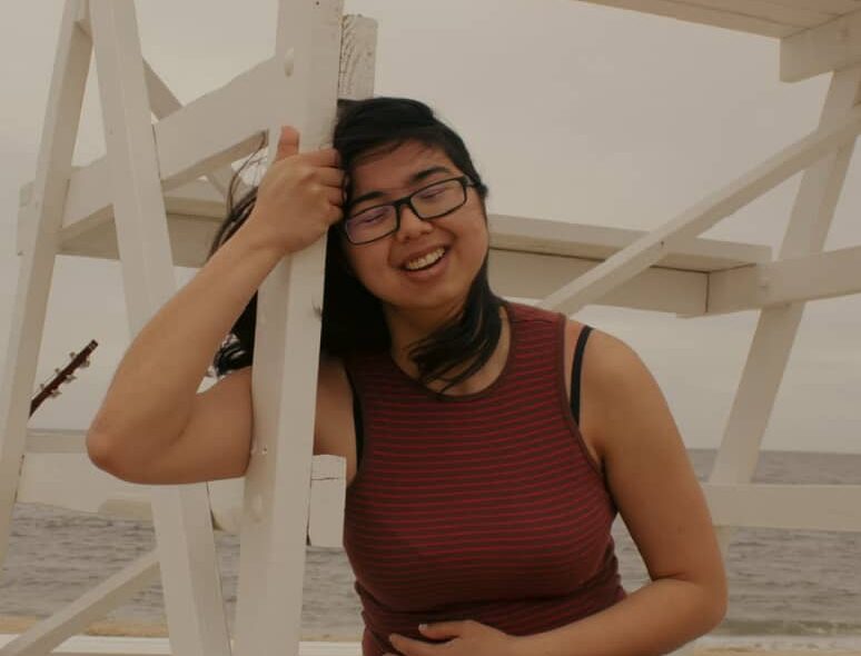 Azure Kai posing against a lifeguard's tower on the beach.