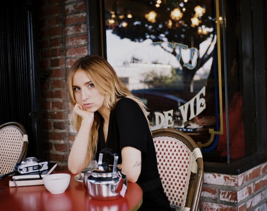 A close-up shot of Emmalee Rainbow sitting in front of a cafe