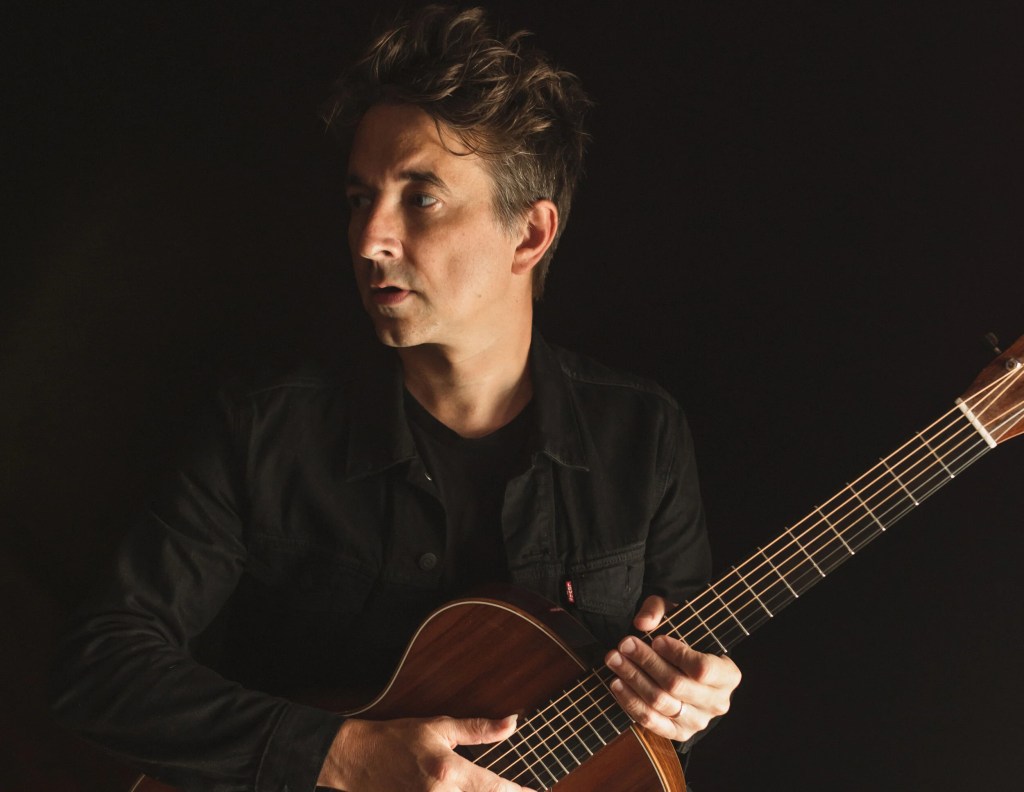 Luke Brindley holding his guitar.