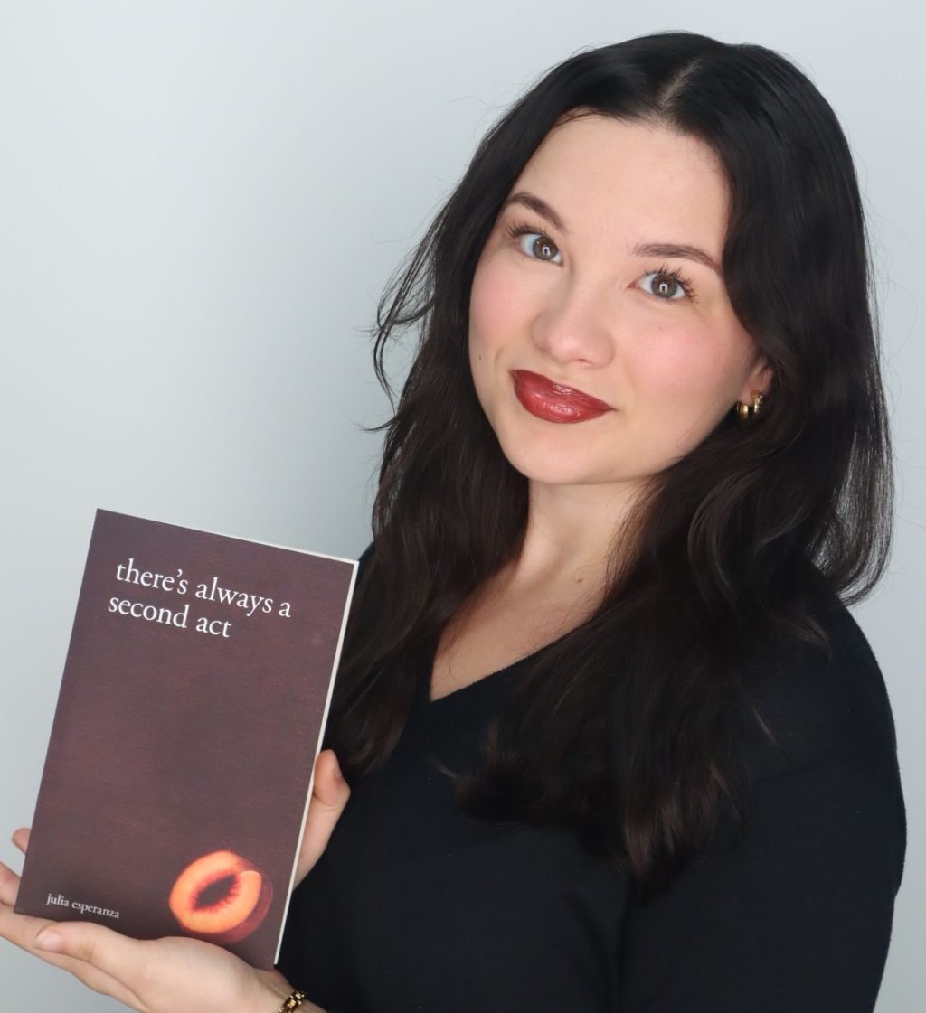 Julia Esperanza, a Latina woman with black hair, poses with her poetry collection, There's Always a Second Act, a small book with a red cover and a sliced peach at the bottom right.