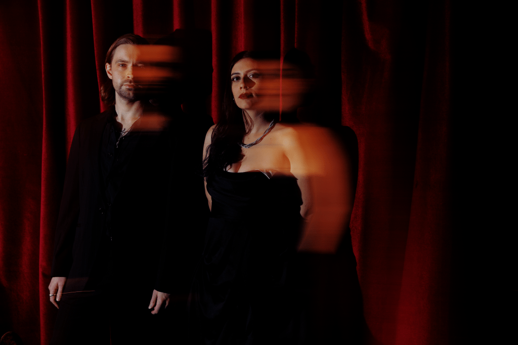 Jamie Thomas and Raquel Bartra of SYLVR posing in front of a red curtain