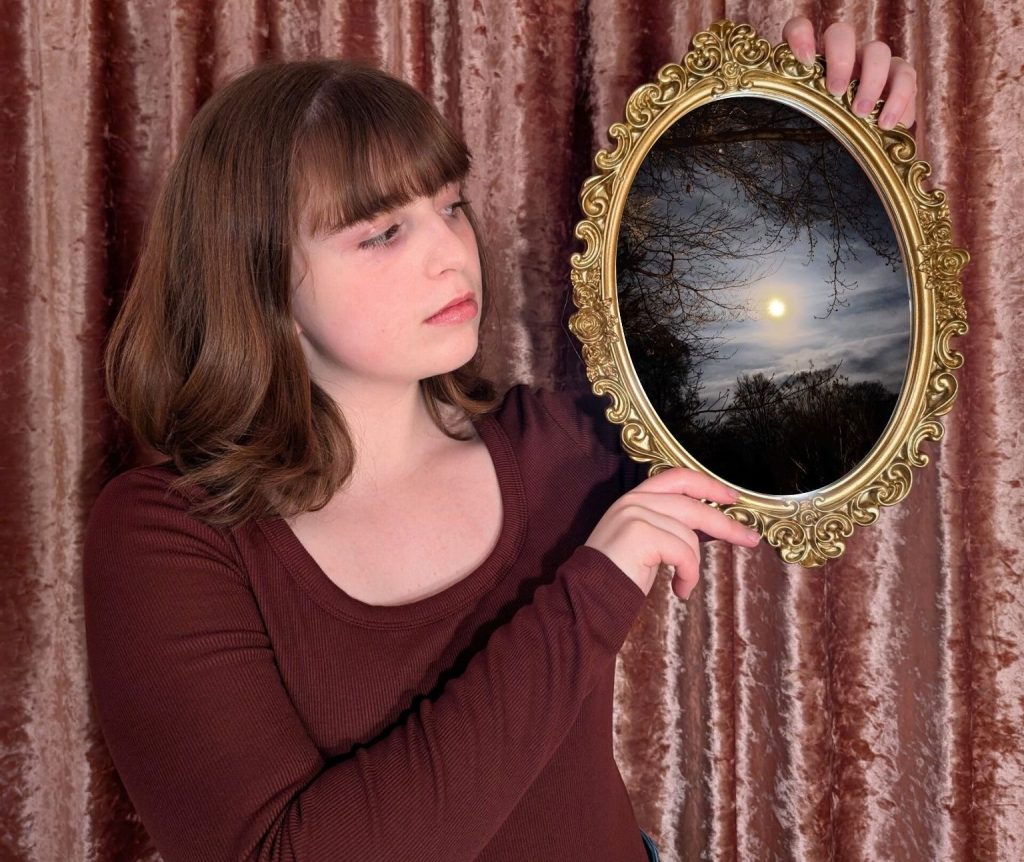 Sydney Schirripa holding a mirror that pictures a moonlit sky