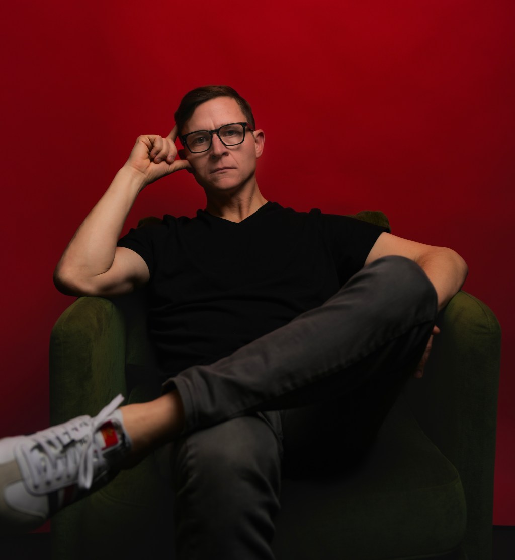 Photo of E.G. Vines sitting in a chair in front of a red wall