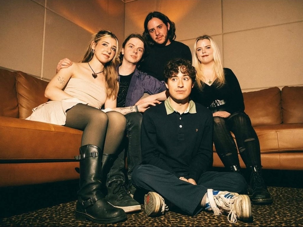 The members of No Soap Radio sitting on a couch